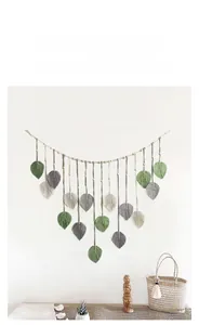 Detail of bohemian handmade woven leaf tapestry with green and white macrame tassels