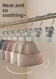 S-shaped stainless steel laundry hooks holding knitted hats against a beige wall