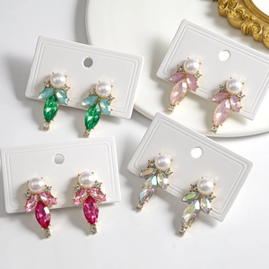 Macro detail of leaf-shaped drop earrings featuring pearls and marquise-cut crystals