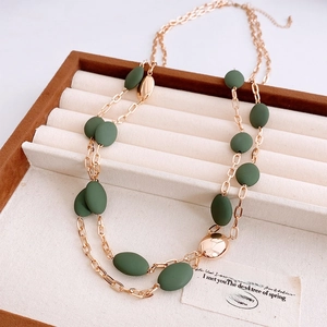 Detail of vintage double-layer necklace with dark green oval beads on a jewelry display tray