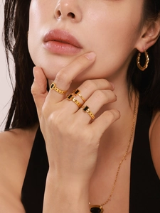 Close-up of elegant gold jewelry set featuring rectangular black shell inlay rings and earrings