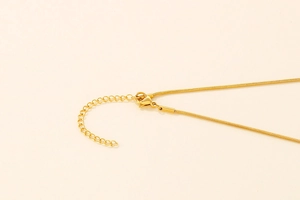 Macro shot of gold lobster clasp and adjustable snake chain detail on the necklace