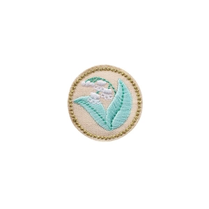 Circular Lily of the Valley floral embroidery patch with gold metallic trim on white