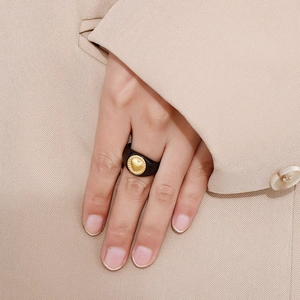 Macro detail of retro black ring with gold heart pattern and beaded edge on model