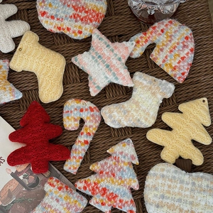 Handmade knitted Christmas tree and star ornaments set on a textured brown background