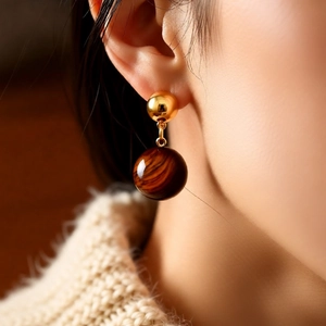 Close-up of 18k gold plated tiger eye stud earrings worn on model for retro vintage look
