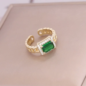 Detailed macro view of an adjustable gold-tone chain ring with a green emerald-cut zircon