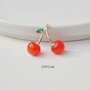 Detail of red cherry pendant charm with golden stem and green leaf measuring 25x31mm