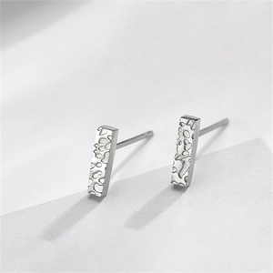 Macro view of silver geometric stud earrings with a detailed water ripple hammered texture