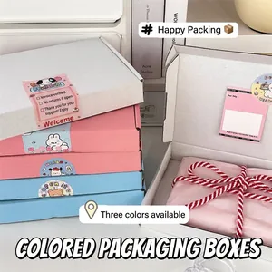 White, pink, and blue shipping boxes with tissue paper, stickers, and cotton twine