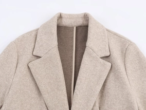 Detailed close-up of light beige soft blazer featuring notched lapels and wool-like texture
