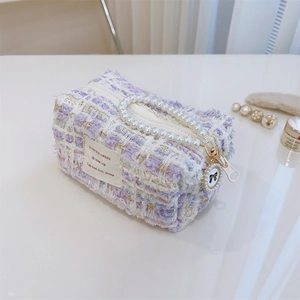 Close-up of purple tweed small square bag with pearl handle and golden zipper detail