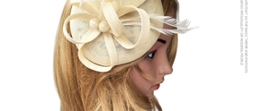 Detail of beige fascinator hat with sisal mesh, elegant pearls and soft feathers