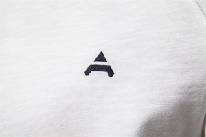 Close-up of white ribbed knit fabric featuring high-quality dark geometric embroidery detail