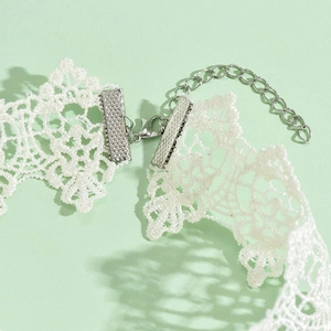 Macro detail of white lace choker showing silver lobster clasp and extension chain