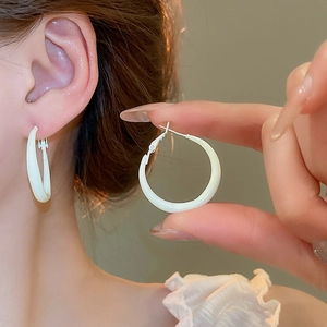 Close-up of minimalist white round hoop earrings with a glossy smooth finish on the model
