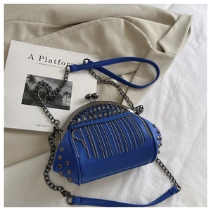 Detail of royal blue shell bag featuring metallic fringe tassels and rivet accents