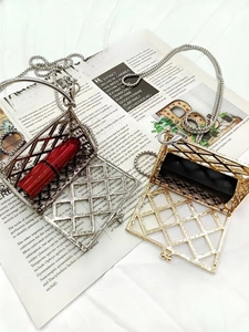 Detail shot of mini cage-shaped pendant necklaces in gold and silver on vintage paper