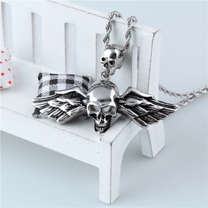 Collier avec pendentif tête de mort ailée en acier titane sur un support décoratif