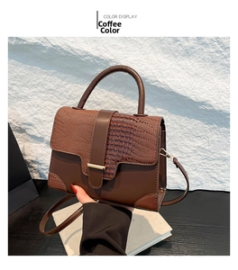 Detail der kaffeebraunen Klappe mit Krokodilprägung und glatter Lederhandtasche