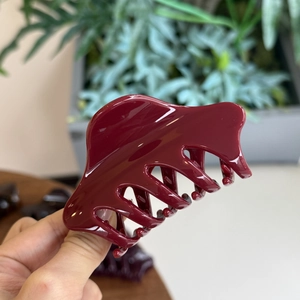 Vue détaillée de la pince à cheveux papillon bordeaux brillant au fini lisse et chic