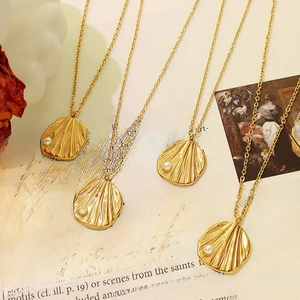 Vintage golden shell pearl pendant necklace on art book background aesthetic