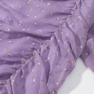 Dettaglio ravvicinato del tessuto chiffon floreale viola con trama elastica arricciata