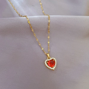 Detailed view of heart-shaped ruby pendant with pavé crystals on gold necklace