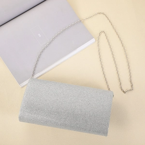 Detail of silver glitter clutch bag with metal chain strap on minimalist background