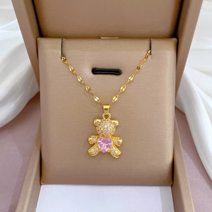 Close-up of golden bear necklace with pink heart gem in a beige jewelry box