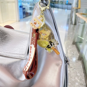 Cartoon Shiba Inu bubble tea keychain with yellow liquid floating on a silver handbag