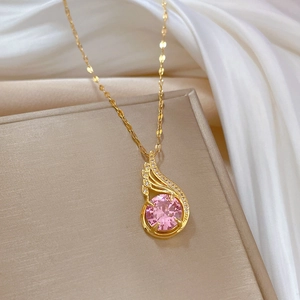 Detail of gold necklace featuring pink teardrop gemstone pendant on silk background