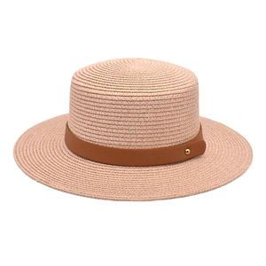 Detail of a woven straw boater hat featuring a brown leather band and gold rivet detail