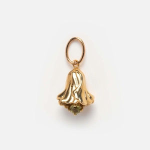 Close-up of gold bell pendant with an inlaid green gemstone on a clean white background