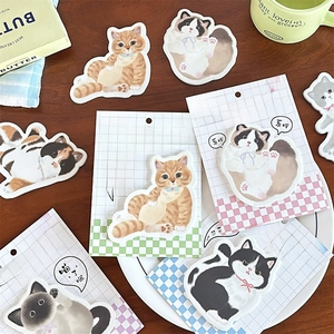 Detailed flat lay of cute cat-shaped sticky notes on wood desk with butter book