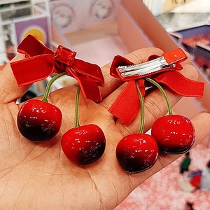 Détail des barrettes à nœud en velours rouge avec cerises et pince crocodile en métal