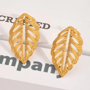 Gros plan détaillé de boucles d'oreilles feuilles dorées évidées avec texture brossée