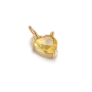 Macro detail of a gold heart pendant featuring a faceted yellow gemstone inlay