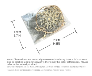 Detail view of a bohemian dreamcatcher with grey feathers and beads in packaging