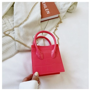 Close-up of pink crocodile textured mini square bag with golden chain strap and top handles