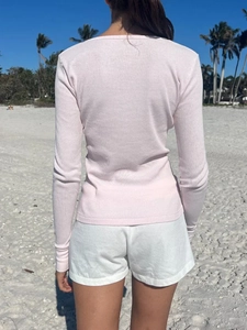 Minimalist pink long sleeve crew neck t-shirt for women shown from a back view on a beach