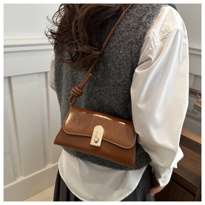 Brown vintage leather shoulder bag with knotted strap and gold buckle worn by model