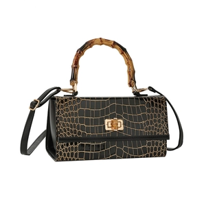 Fashionable black crocodile pattern handbag with bamboo handle and gold twist lock closure