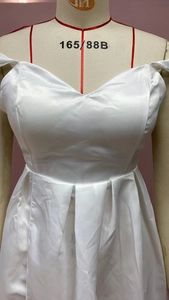 Detail of white satin dress featuring a sweetheart neckline and elegant pleated skirt finish