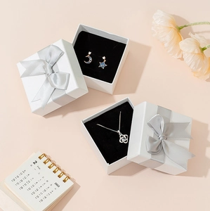 Elegant white jewelry gift box with grey ribbon featuring floral necklace and moon earrings