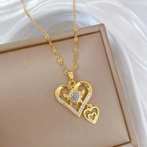 Close-up of golden double heart pendant with round zircon on white satin jewelry box