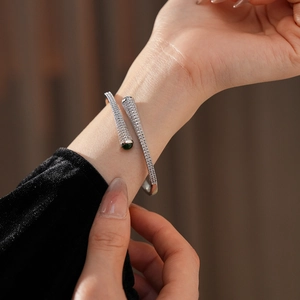 Detail of silver plated cuff bracelet with pave zircons and green gemstone accent