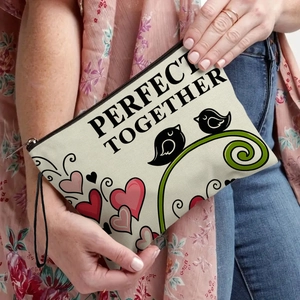 Beige canvas makeup bag with bird print and Perfect Together text held by a model