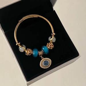 Golden twisted cable bracelet with blue glass beads and sparkling evil eye crystal charm
