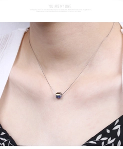 Close-up of a blue gradient cube crystal pendant on a S925 silver chain worn by a model